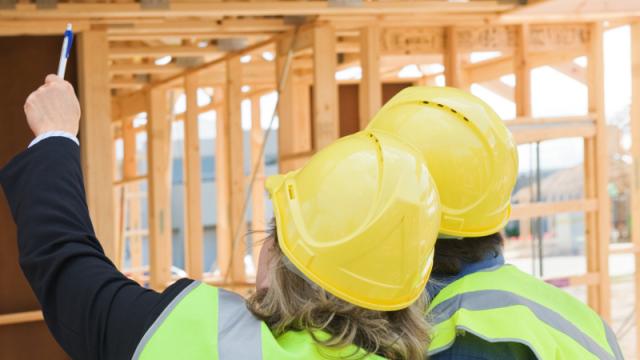 house frame work being inspected by construction workers