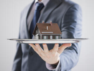 agent holding a tiny home on a platter out in front of him