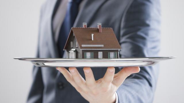 agent holding a tiny home on a platter out in front of him