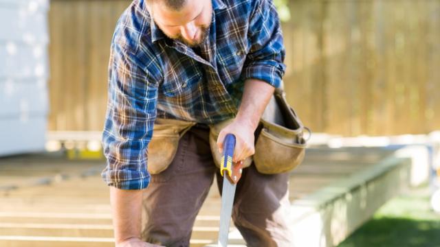 man cutting treated lumber for a deck