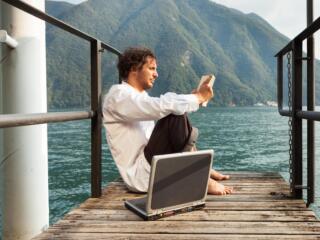 man reading on lake with laptop