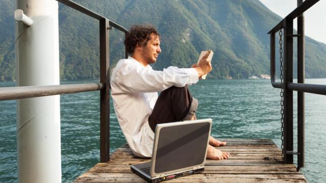 man reading on lake with laptop