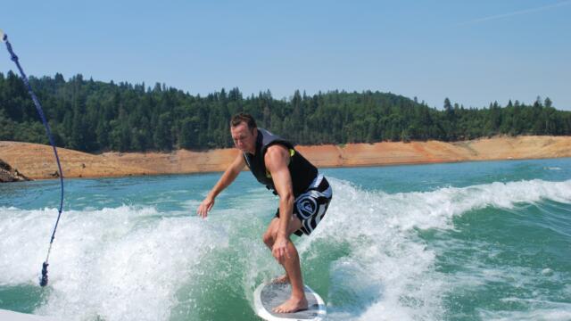 man wakesurfing behind a boat on the lake