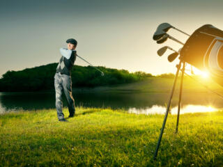 golfer in mid-swing with golf bag in foreground, player in background
