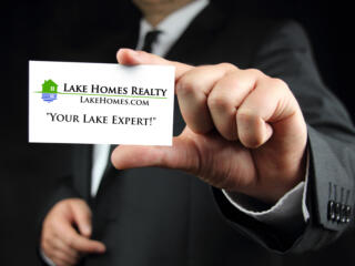man in a suit holding out a Lake Homes Realty Lake Expert