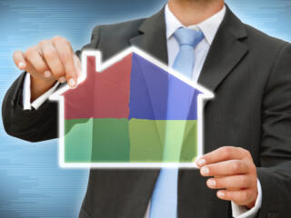 man in suit holding an outline of a house, filled with colored panes.