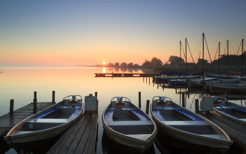 three boats docked at sunset