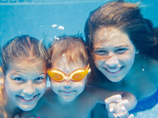 three kids smiling under water