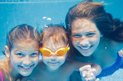 three kids smiling under water