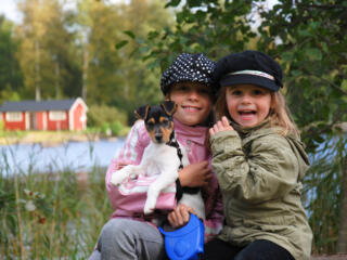 2 little girls sitting by the lake holding a puppy
