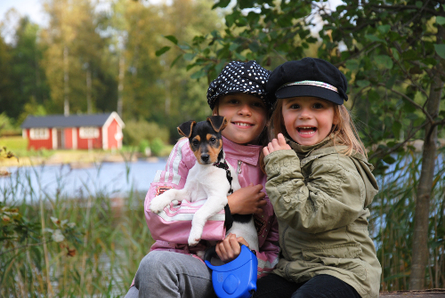 2 little girls sitting by the lake holding a puppy