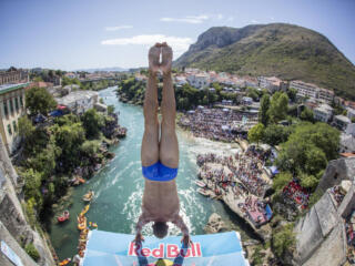 male cliff diver in handstand position on platfrom