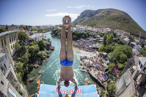 male cliff diver in handstand position on platfrom