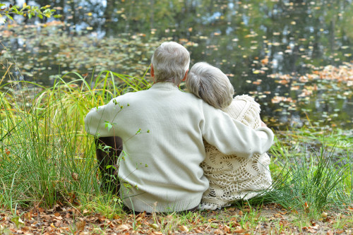 elderly couple hugging next to lake-sm