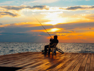 man fishing on the dock at sunset