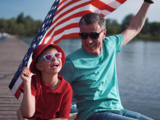 father and son on dock holding American flag