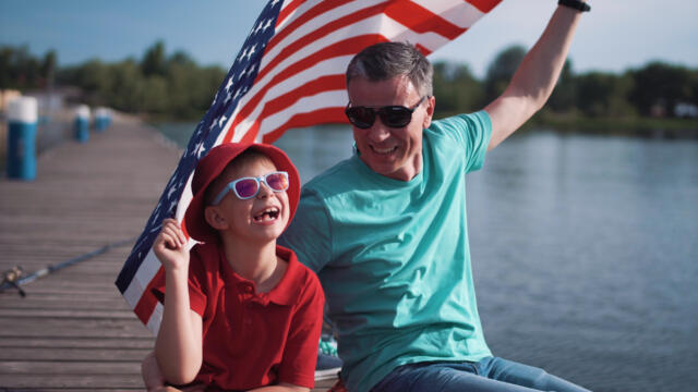 father and son on dock holding American flag
