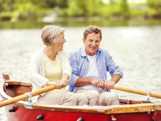 older couple enjoying lake living while rowing a boat