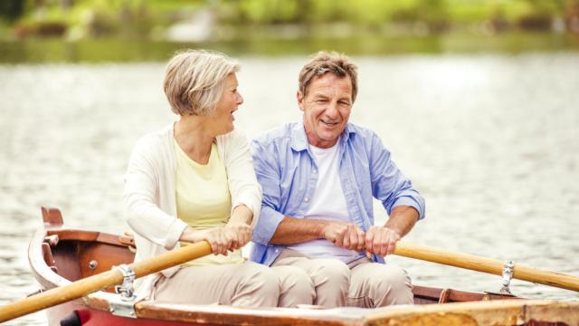 older couple enjoying lake living while rowing a boat