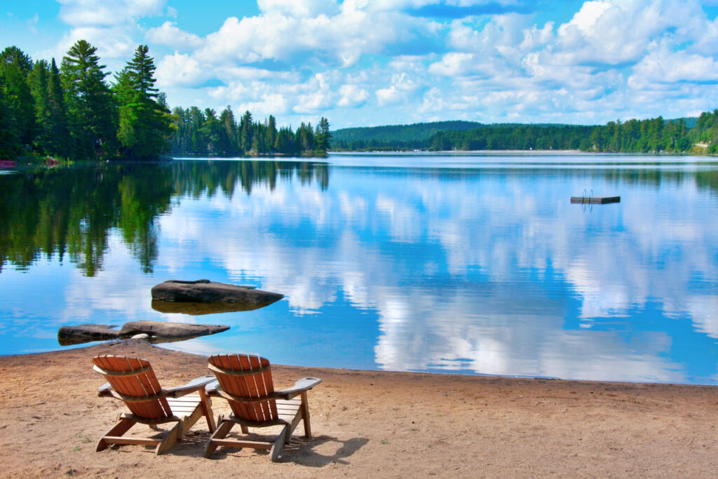 deux chaises longues en bois sur la rive du Douglas Lake avec des nuages se reflétant sur l'eau