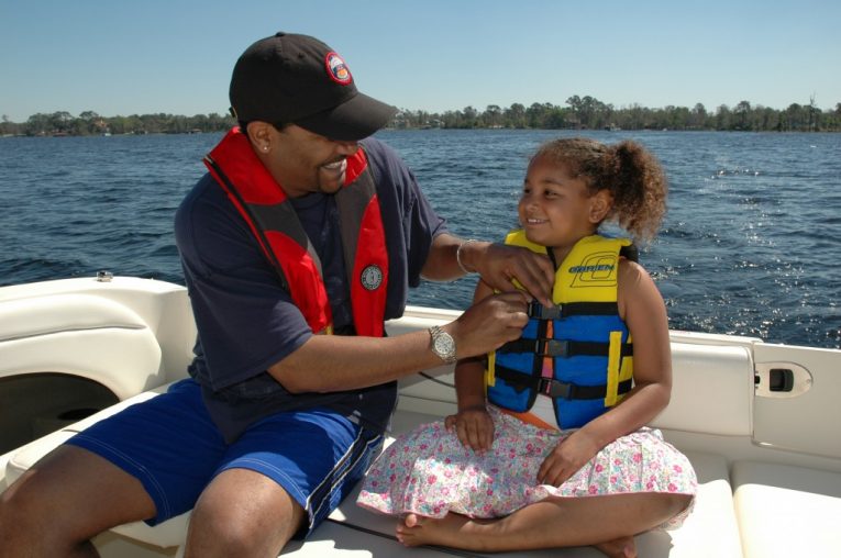 Father helping daughter inspect life jacket personal flotation device