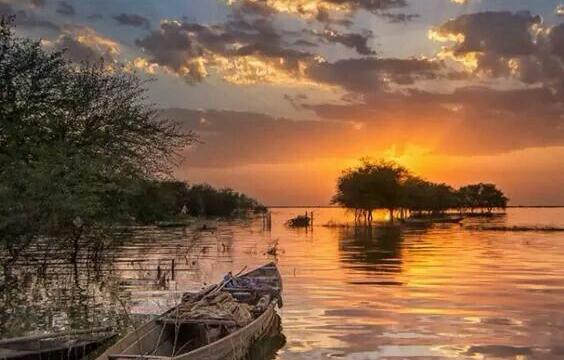 canoe on lake during sunset with clouds