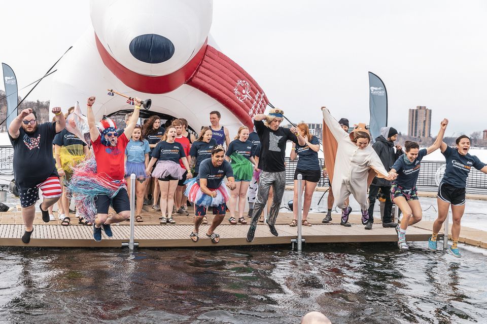 Polar plunge in Minnesota, featuring many people jumping into the lake with an inflatable polar bear behind them.