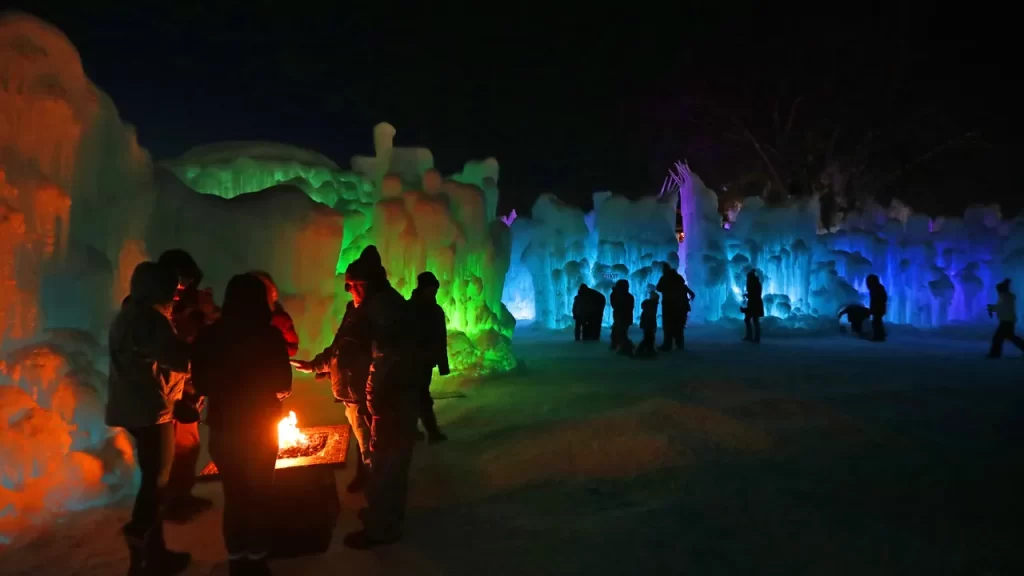 Ice castles lit up by red, green, blue, and purple lights situated on Lake Geneva in Wisconsin. 