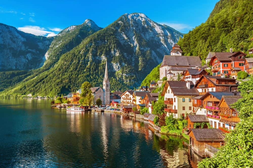 Lake Hallstatt, Austria with quaint houses and a church plus tall mountains in the background. 