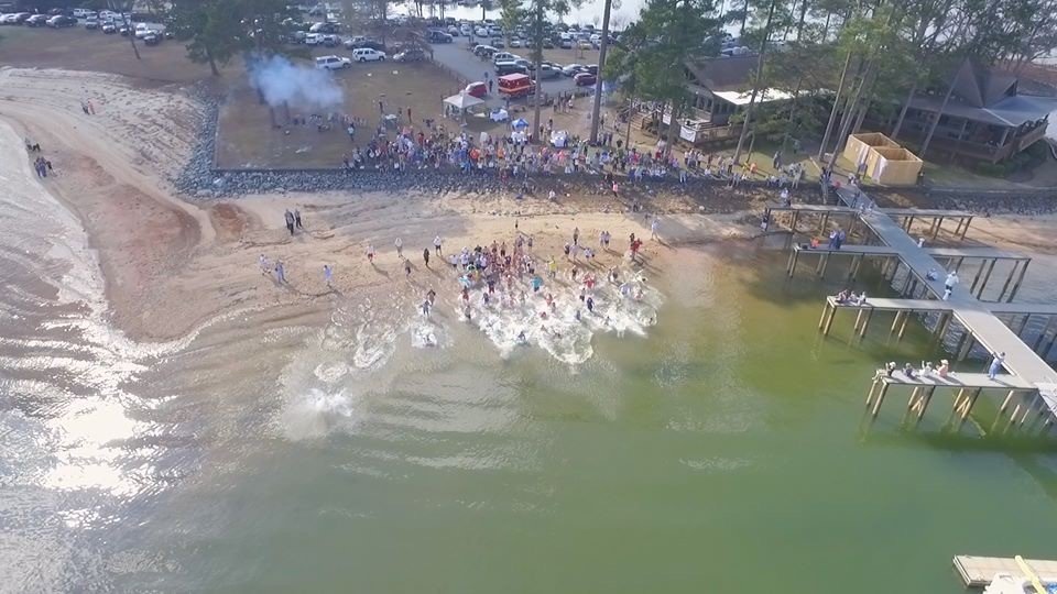 Lake Martin's winter event where people jump in the lake to support the protection of the waters and habitat. Picture is an aerial shot of people running into water. 