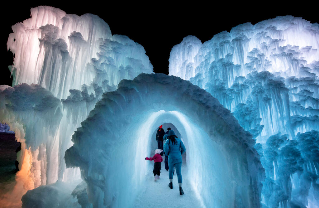 Family walking through tunnel surrounded by ice structures. 