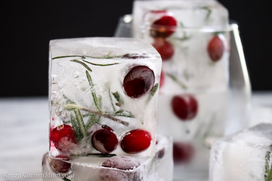 Large holiday ice cubes with cranberries and rosemary frozen in them.
