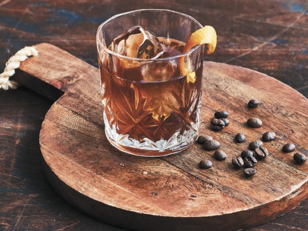 Coffee Old Fashioned on a wooden cutting board in a glass with an orange slice. 