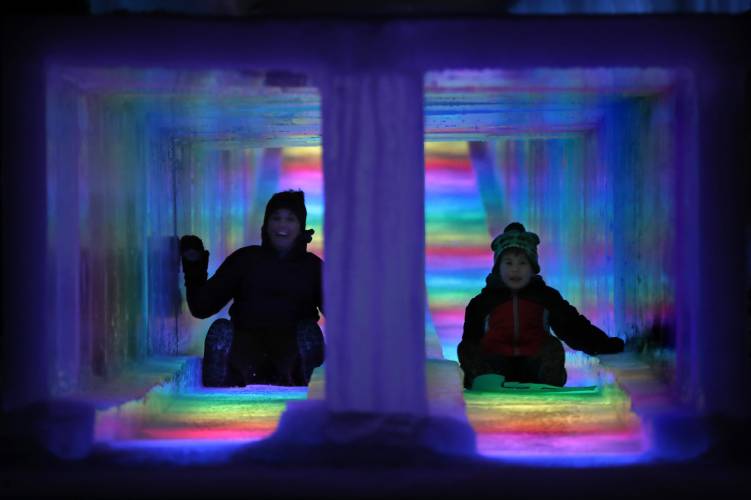 Mother and child going down colorful ice slide. 