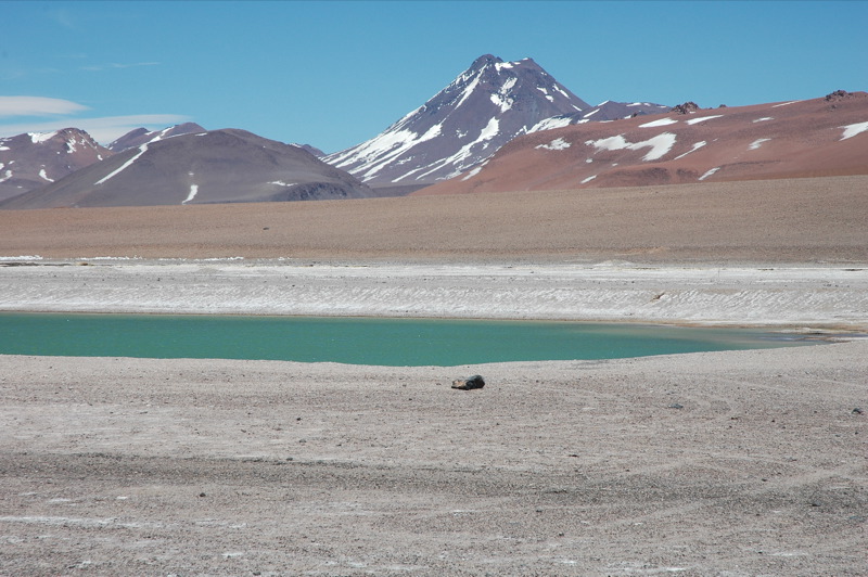 Clear body of water in front of tall volcano. 
