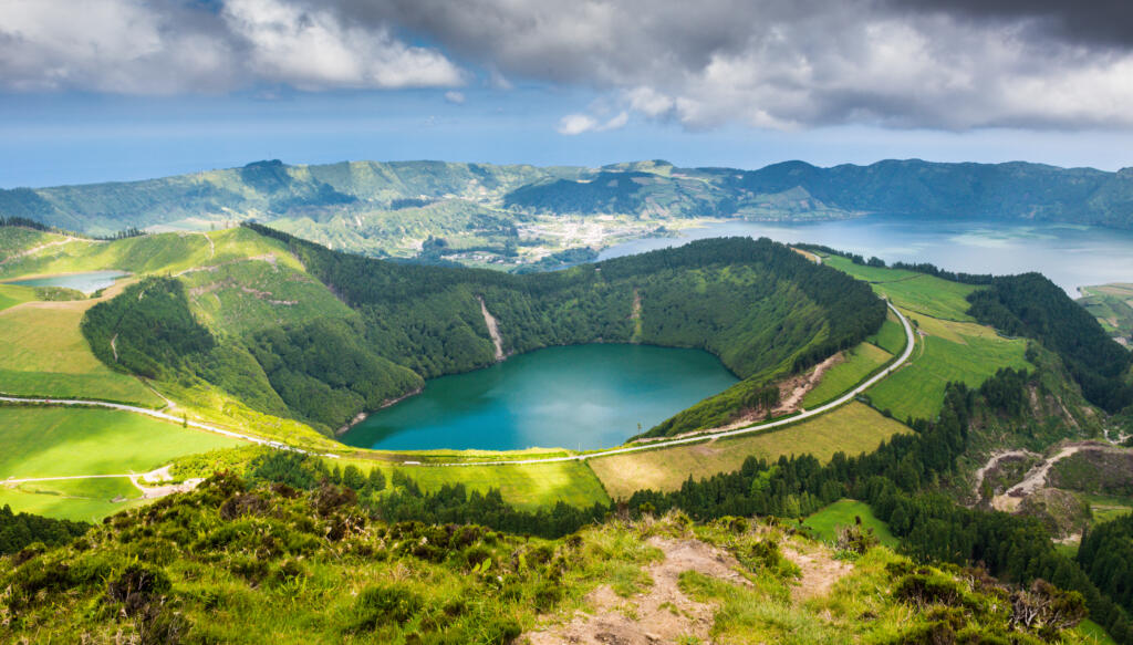 Crater Lake on a green hill with a larger lake in the background. 