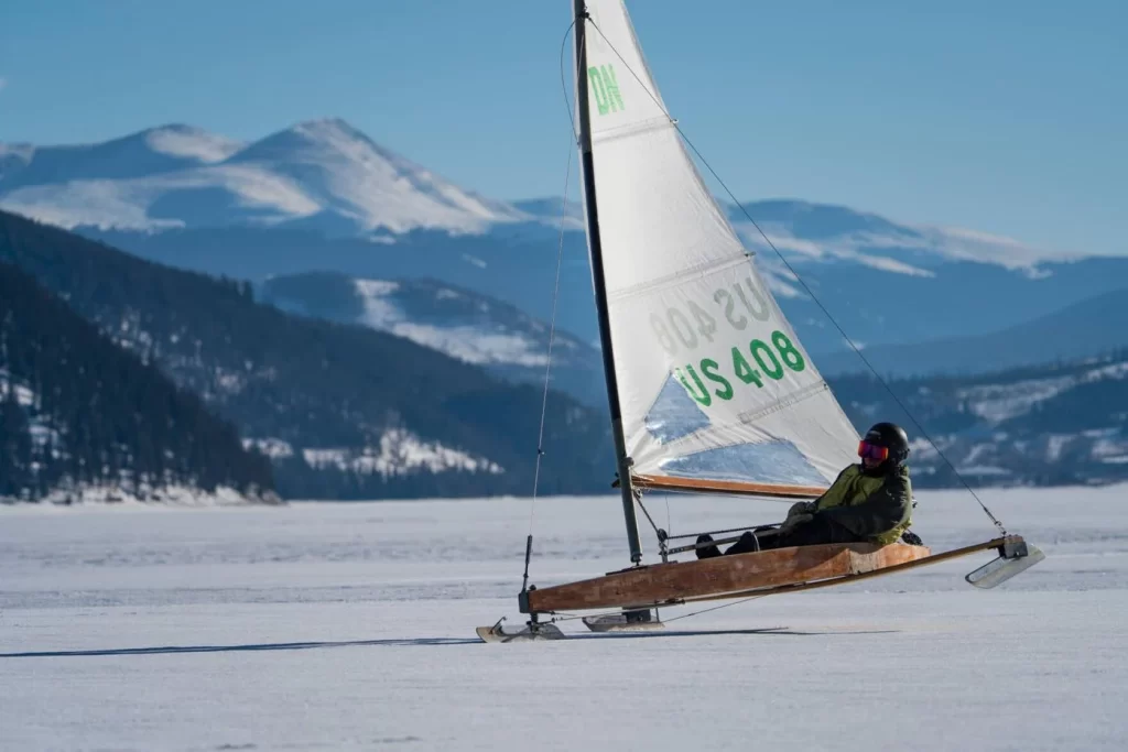 Man sailing in ice boat with mountains behind him