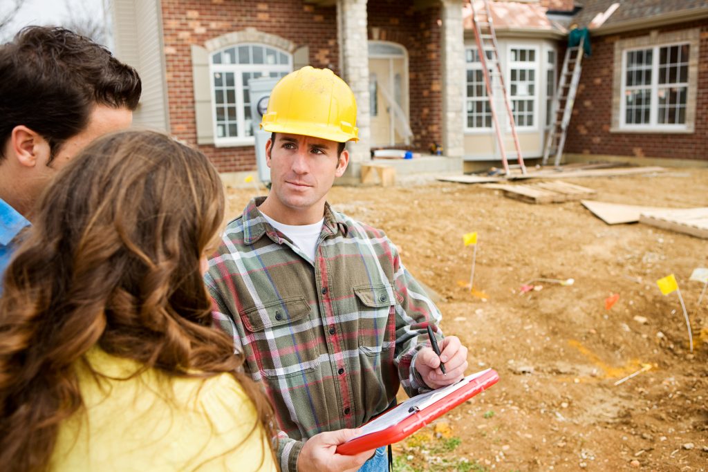 Contractor talking to couple in front of renovated house