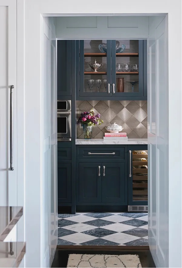 butler's pantry with blue cabinetry, stainless steel backsplash, built-in refrigerator, glassed cabinets, built-in microwave, black and white marble tile floor