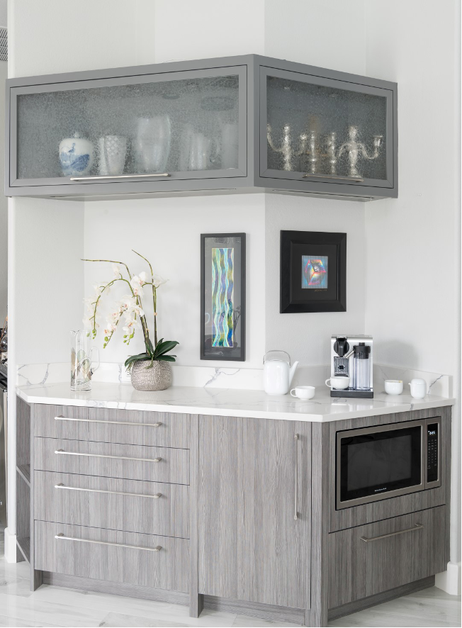 coffee bar in kitchen with gray cabinetry, white and gray marble countertop, built-in microwave, drawers, cupboards, storage cabinets above countetop