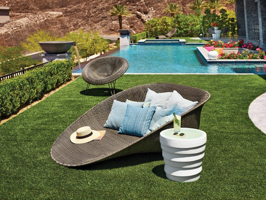 Extra-wide lounge chair in grass by swimming pool