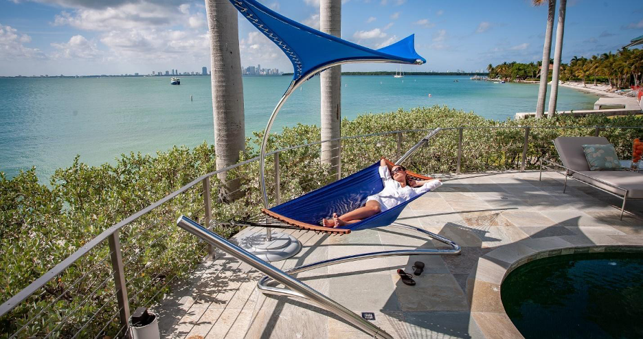 Tucci Air Lounge + Wave Stand, blue modern hammock with curvy metal stand by the beach, woman lounging in hammock