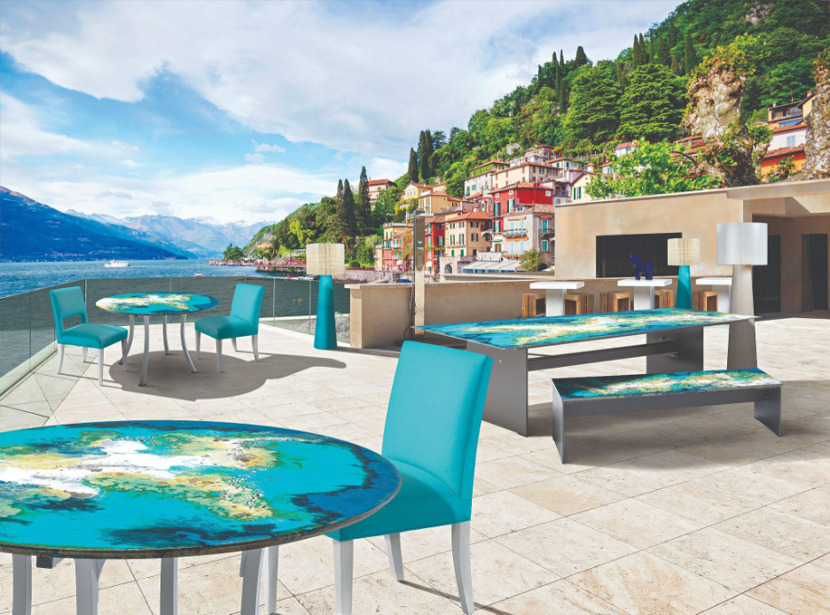 Outdoor Etna Round dining table with layers of glaze colors in bright turquoise, blues, green, yellow, and white on terrace by beach