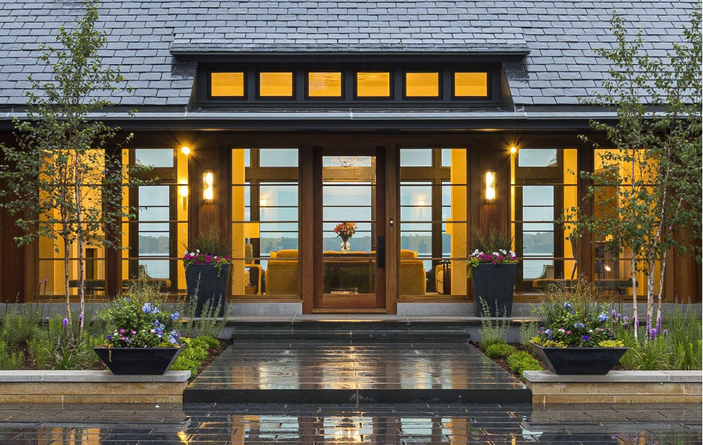 Curb Appeal, front door of lake home with view to the lake, brick walkway entrance, potted flowers, green foliage flanking walkway