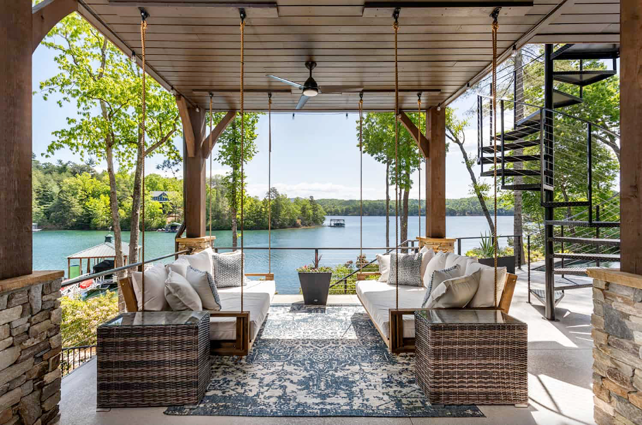 covered patio with porch swing beds, wood beam ceiling, stone pavers on Lake Keowee landscape
