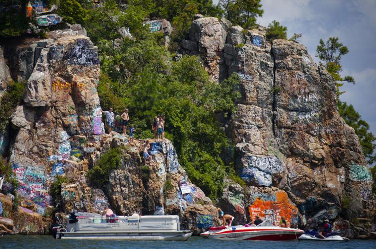 people and boats in front of a cliff