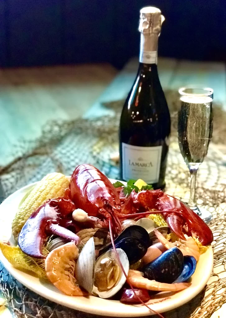 Seafood boil with lobster, shrimp, mussels, clams, corn on the cob with champagne