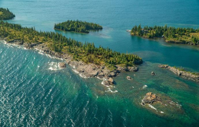 an aerial shot of an island with trees in Lake Superior