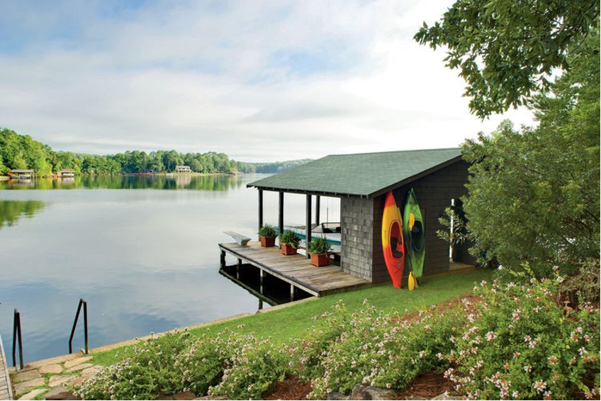 Boat House in lake with bright kayaks up against building, beautiful lake landscape