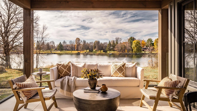 covered patio with sofa, chairs, and round metal cocktail table with lake setting in background